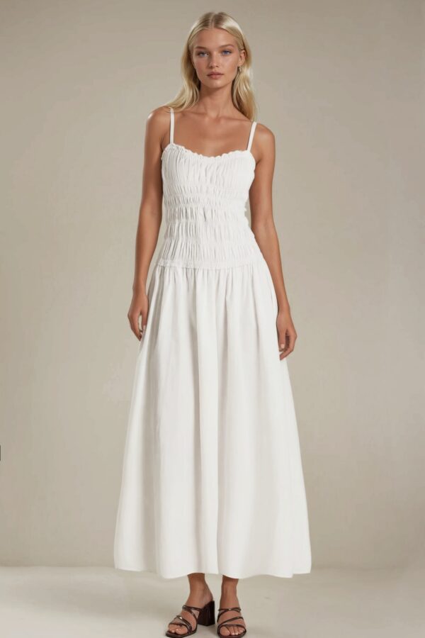Woman wearing a white smocked bodice maxi dress with spaghetti straps and flowy skirt
