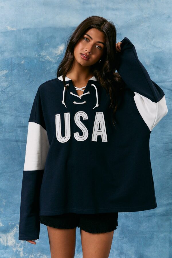 Woman wearing navy oversized USA hockey sweatshirt with lace-up neckline