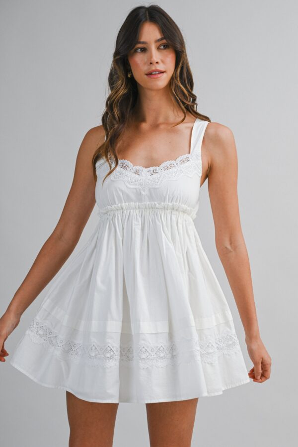 Woman wearing a white eyelet lace trim empire waist babydoll mini dress