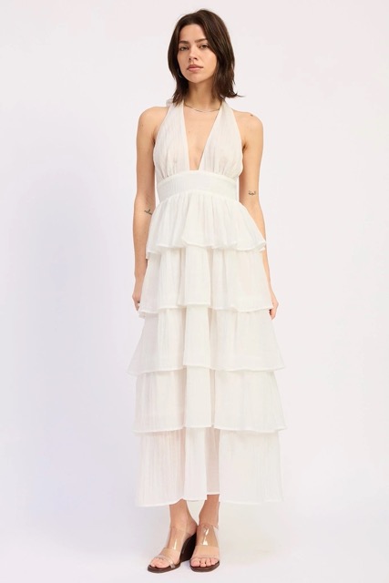 Woman wearing a white halter tiered midi dress with open back and ruffle layers