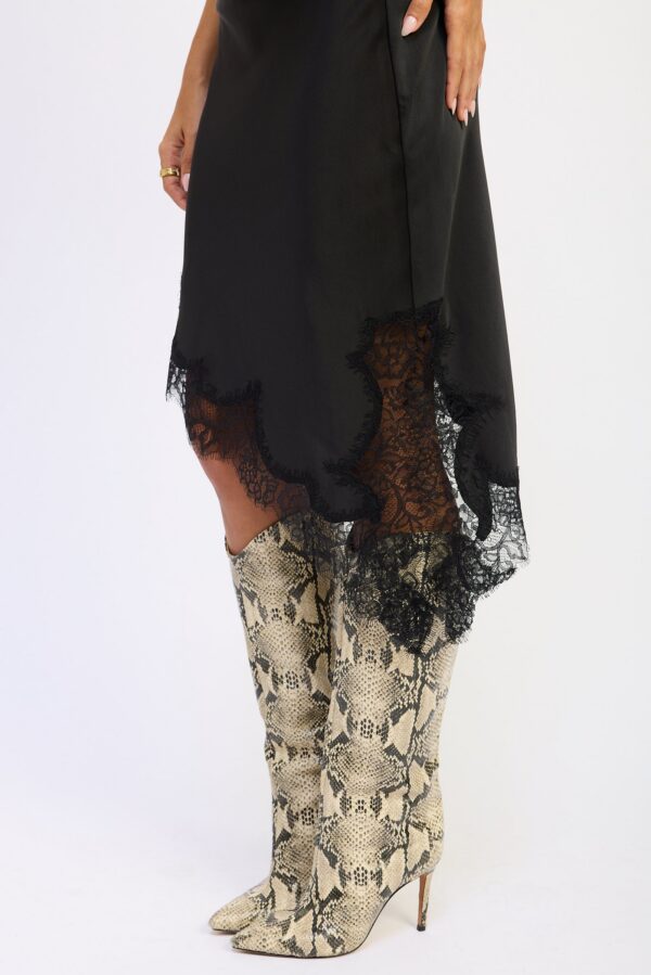 Black skirt with a low-rise silhouette, asymmetrical line, satin finish, and lace detail styled for a women’s boutique fashion look