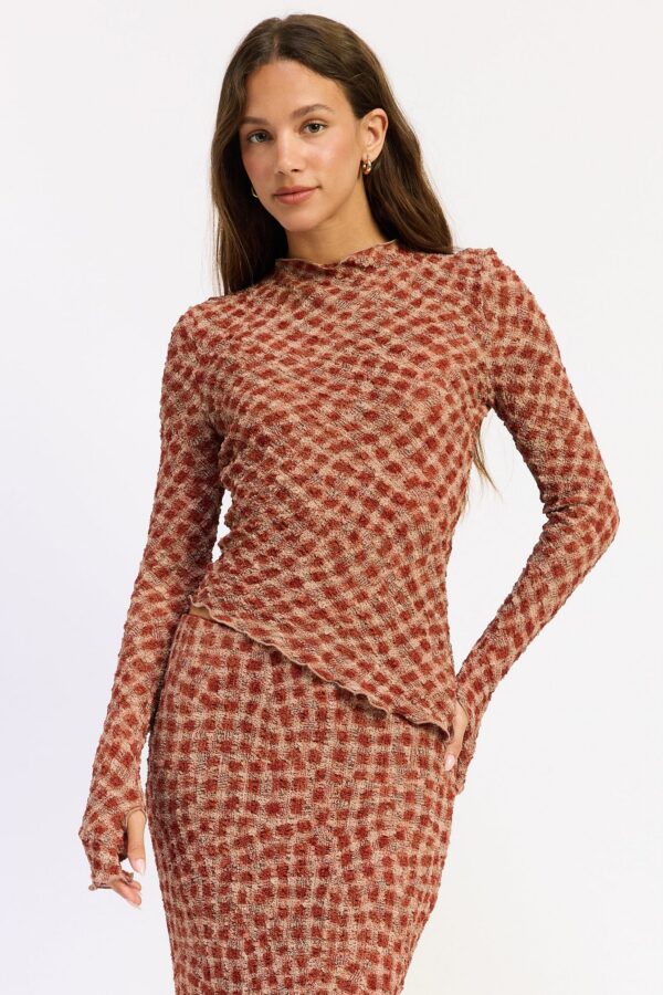 Model wearing cinnamon asymmetrical long sleeve top; an asymmetrical silhouette and long sleeves