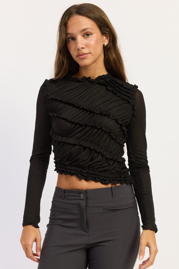 Model wearing black asymmetrical smocked long sleeve top; asymmetrical shaping and smocked texture with long sleeves